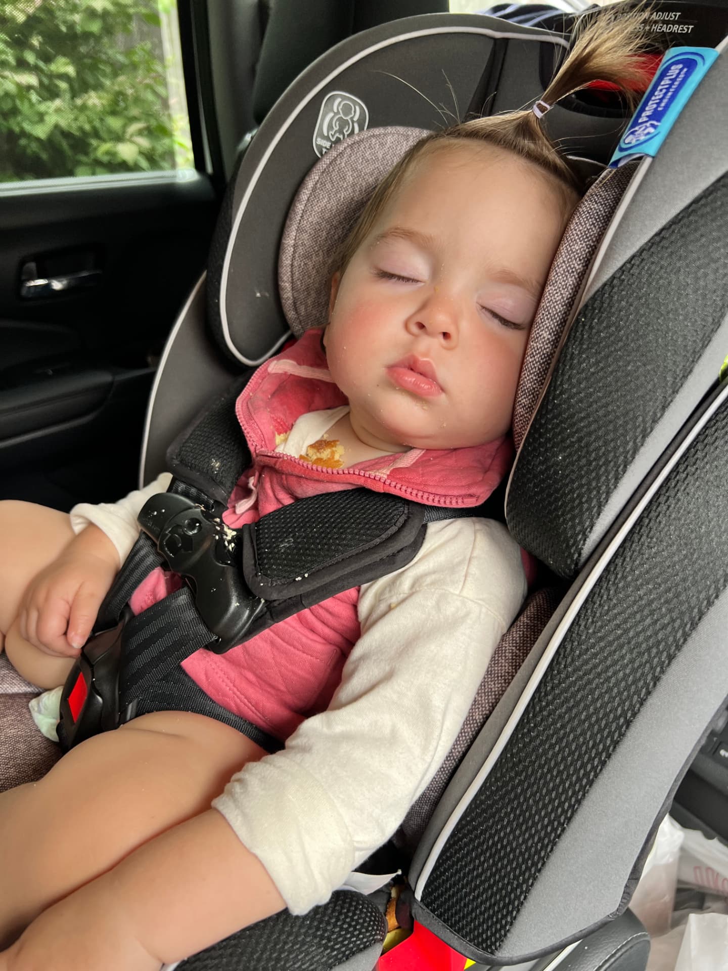 A toddler fast asleep in her car seat on a car ride