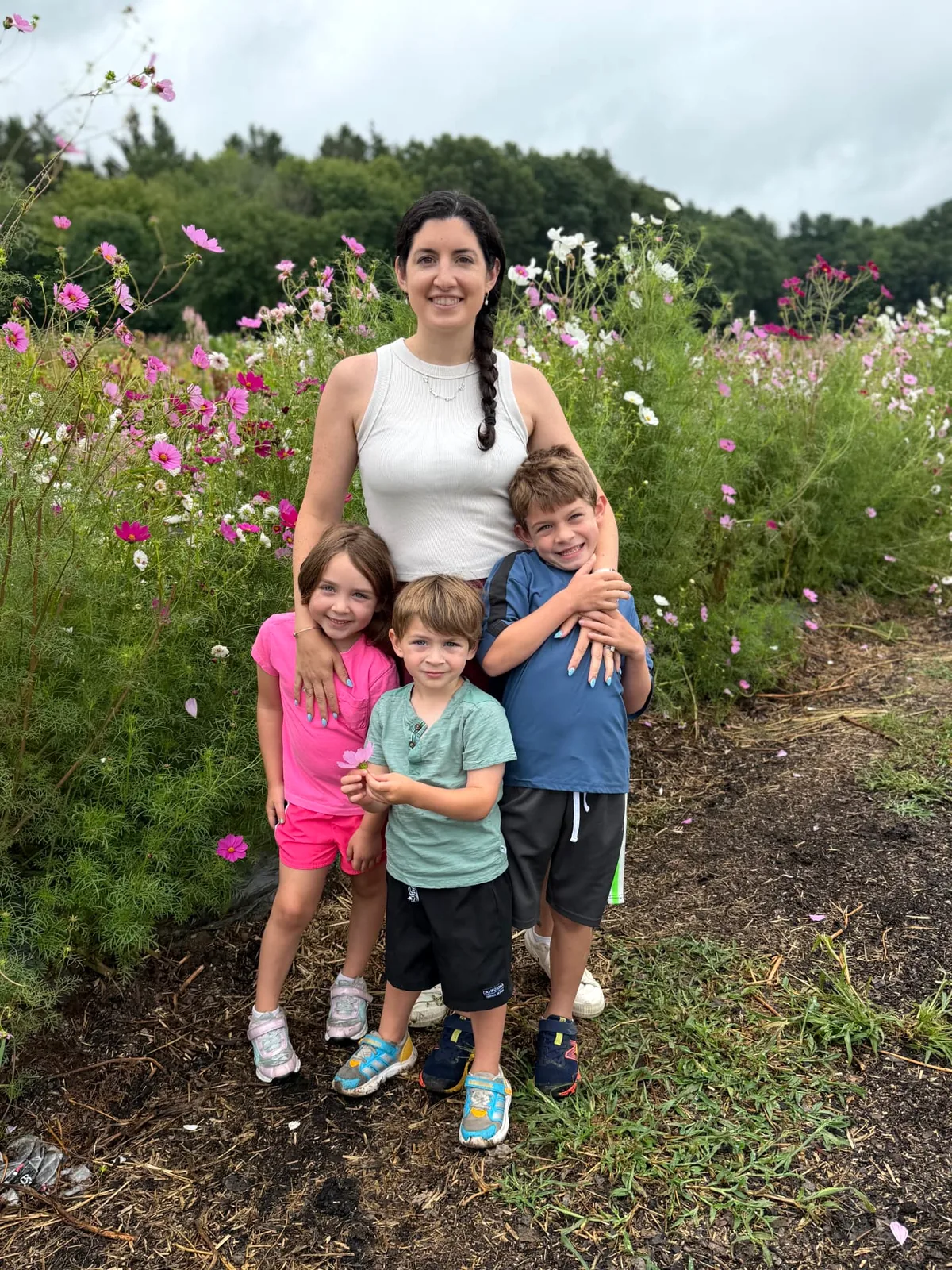 Bethany Barba with three of her children among cosmos flowers in a garden